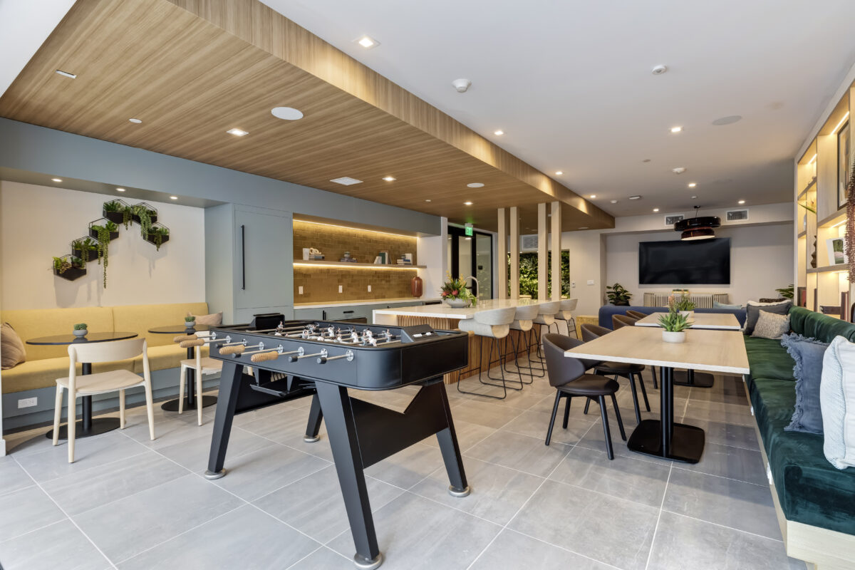 common area with bar, football table, TV, and shelf wall with decor