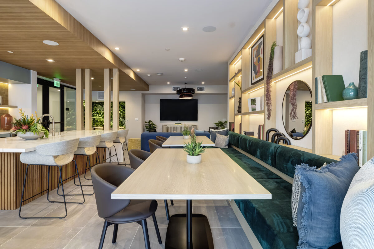 common area with bar stools, TV, and shelf wall with decor