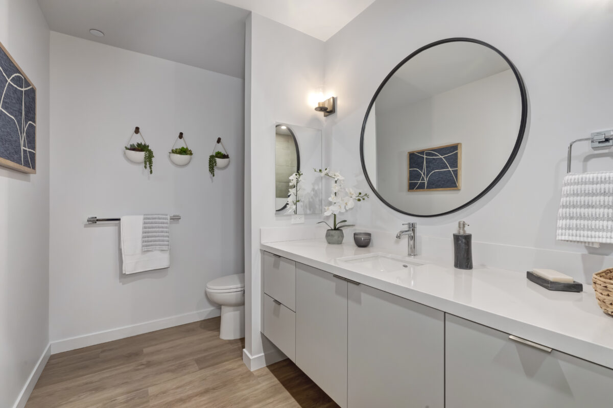 bathroom with white counters and circle mirror